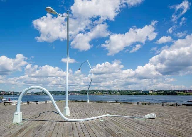 Escultura de farolas inclinadas en el muelle de Halifax bajo un cielo azul con nubes