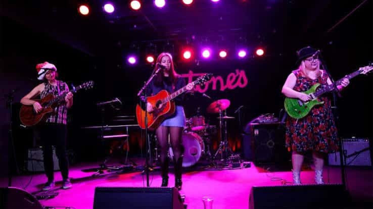 Mujer tocando guitarra acústica en el escenario de Antone's Nightclub con iluminación de colores