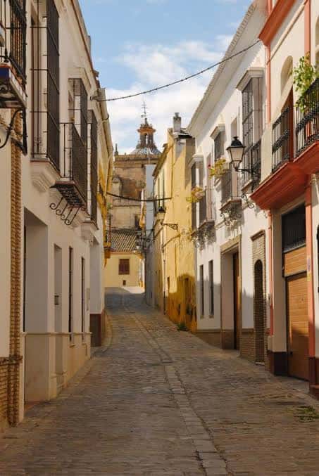 Calle empedrada con edificios blancos y balcones de hierro forjado