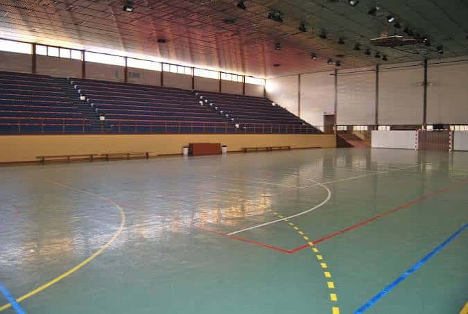 Pabellón deportivo interior con gradas azules y pista de baloncesto