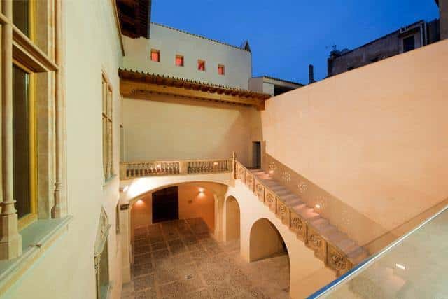 Patio interior de Ca n'Oleo con escalera y arcos iluminados al atardecer