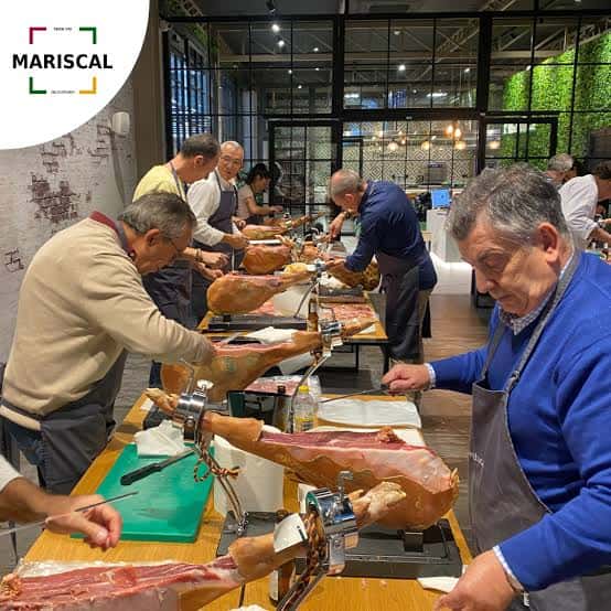 Taller de corte de jamón con participantes y jamones Mariscal Delicatessen