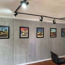 Interior de la galería con paredes de madera y obras de arte enmarcadas