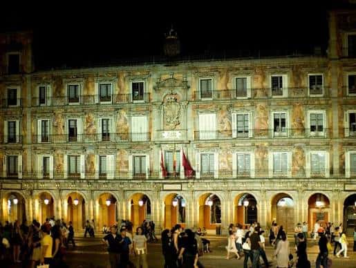 Vista nocturna iluminada de la Casa de la Panadería con público en la plaza