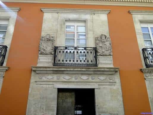 Detalle arquitectónico del balcón central con escudos y puerta de entrada