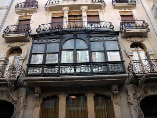 Vista detallada de la fachada principal con balcones y ventanales art nouveau