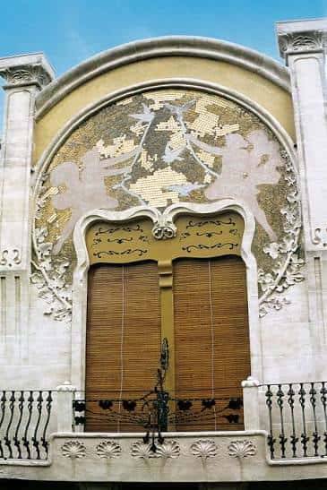 Detalle arquitectónico superior con mosaico decorativo y ventanas