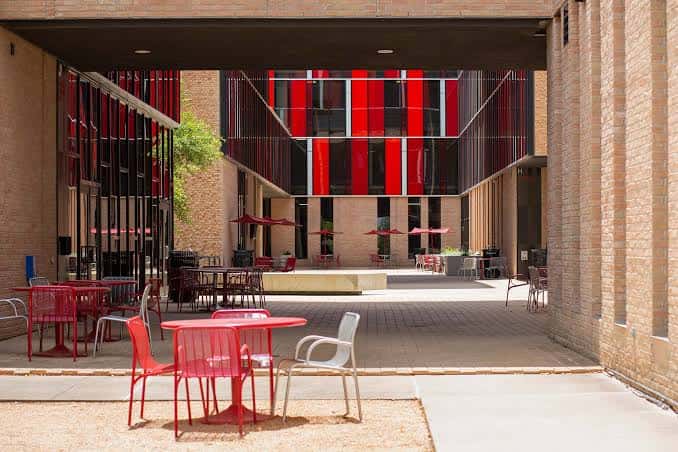 Patio interior del Fine Arts Center con mesas rojas y arquitectura contemporánea