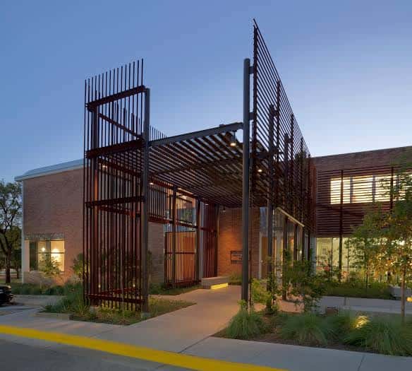 Entrada contemporánea con pérgola metálica y paisajismo integrado al atardecer