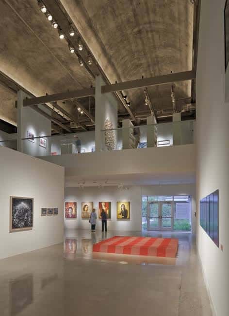 Interior de la galería principal con techos altos, iluminación profesional y obras expuestas