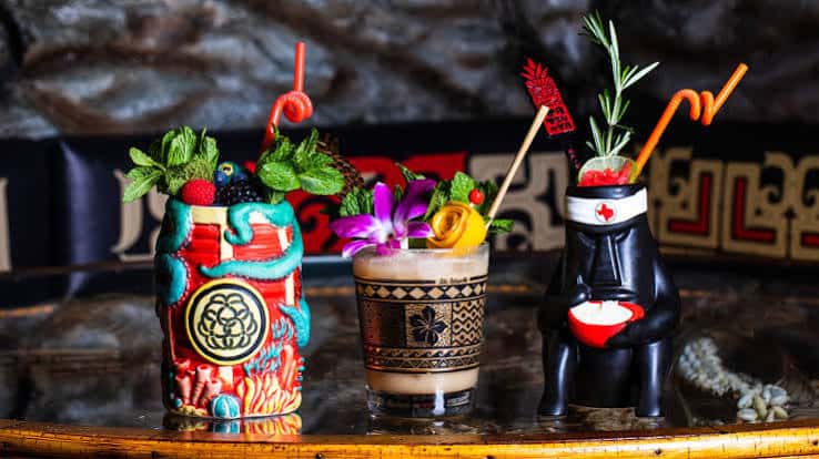 Cócteles temáticos en vasos tiki elaborados sobre la barra