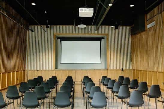 Sala interior configurada como auditorio con proyector y butacas