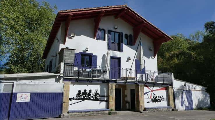 Fachada del Club de Remo Txomin Enea con detalles arquitectónicos tradicionales y murales deportivos