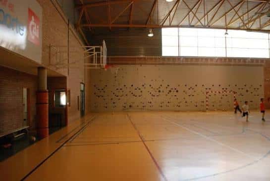 Vista interior del pabellón deportivo con cancha de baloncesto y escalada