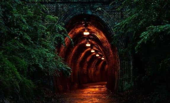 Vista nocturna de la entrada al túnel de ladrillo con iluminación cálida