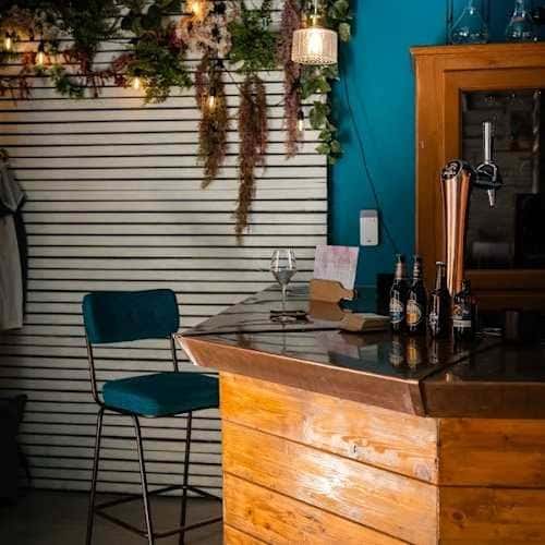 Barra de madera con botellas y vaso de vino en el interior de Amarone by Vinalium