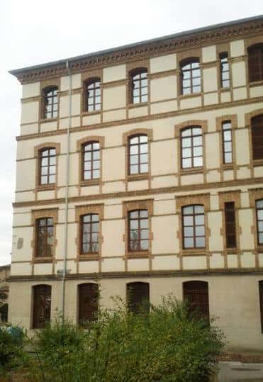 Vista frontal del edificio con ventanas y detalles arquitectónicos