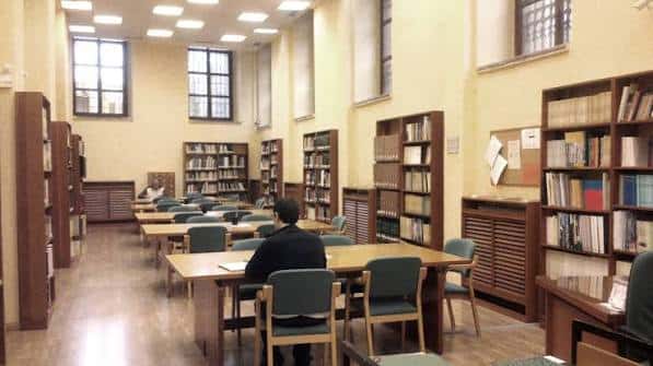 Interior de la sala de lectura con estanterías y mesas de trabajo