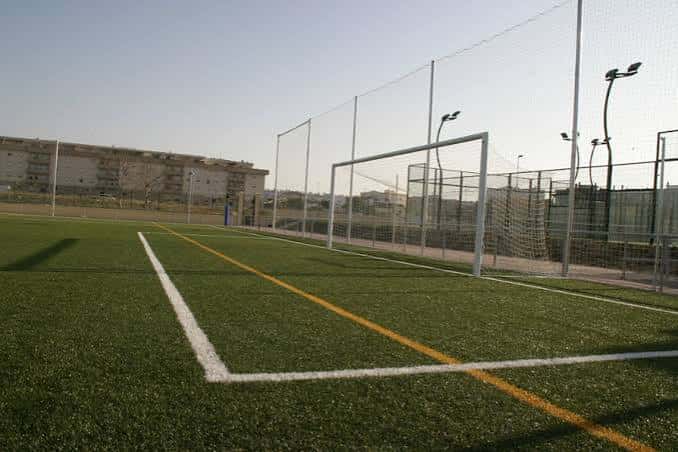 Campo de fútbol con césped artificial y portería bajo cielo despejado