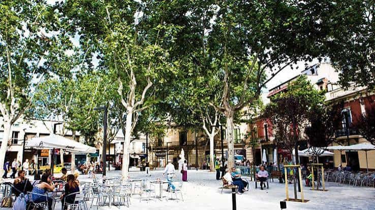 Plaza llena de gente disfrutando en las mesas al aire libre