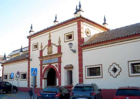 Ángulo lateral de la fachada con estuco blanco y acentos rojos típicos del estilo andaluz