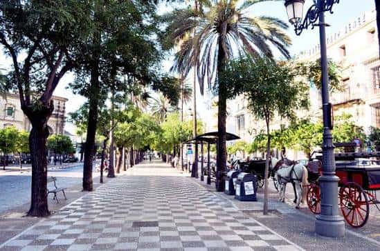 Paseo central de la Alameda Cristina con árboles y carruaje tradicional