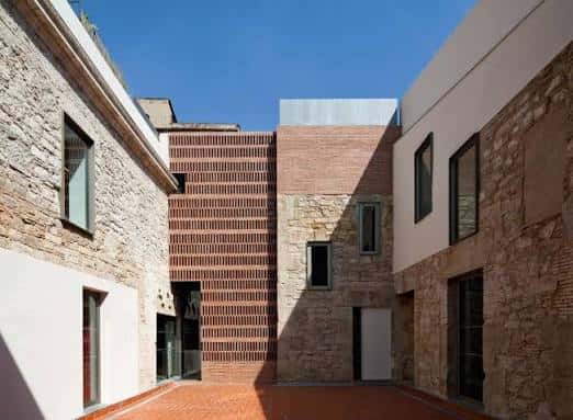 Vista arquitectónica del patio interior con fachadas de piedra y ladrillo