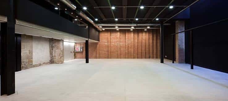 Espacio expositivo amplio con paredes de ladrillo y suelo de hormigón