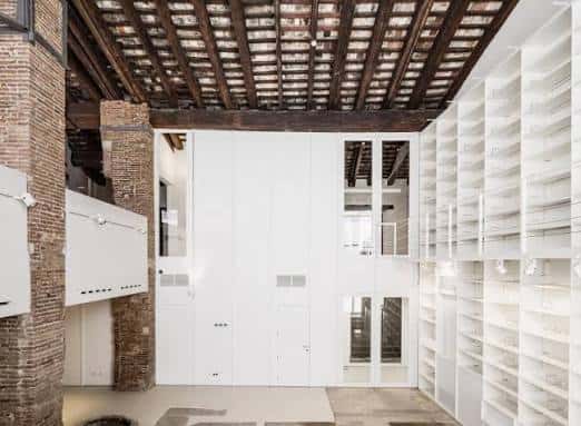 Sala interior con techos de vigas de madera originales y estanterías blancas