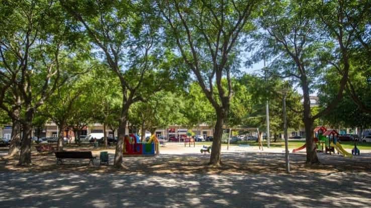 Vista panorámica del parque de las Magnòlies con árboles frondosos y juegos infantiles coloridos