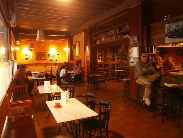 Interior acogedor de la cafetería Ítaca con mesas y estanterías llenas de libros