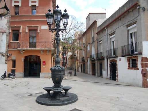 Vista diurna de la Plaça de Santes Creus con farol ornamental en el centro
