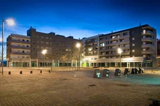 Vista nocturna de la Plaça dels Rabassaires con edificios residenciales iluminados