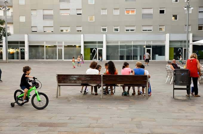Plaza durante el día con personas disfrutando del espacio público y bancos