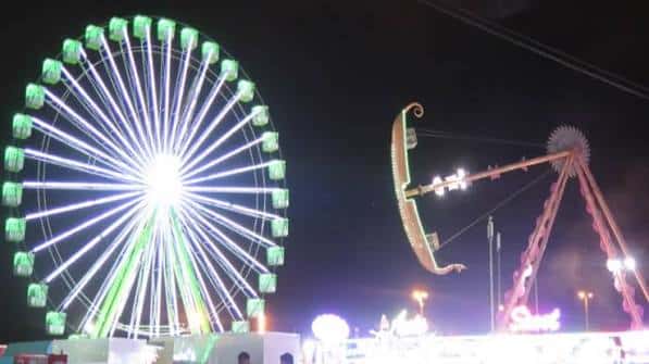 Vista nocturna de atracciones de feria iluminadas en el recinto