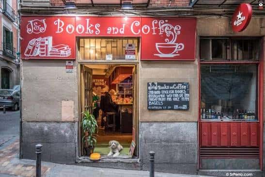 Fachada de J&J Books and Coffee con letrero rojo y un perro en la entrada