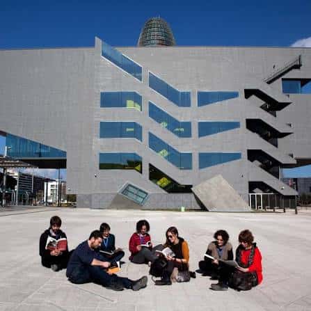 Grupo de personas leyendo en el patio exterior frente a la biblioteca