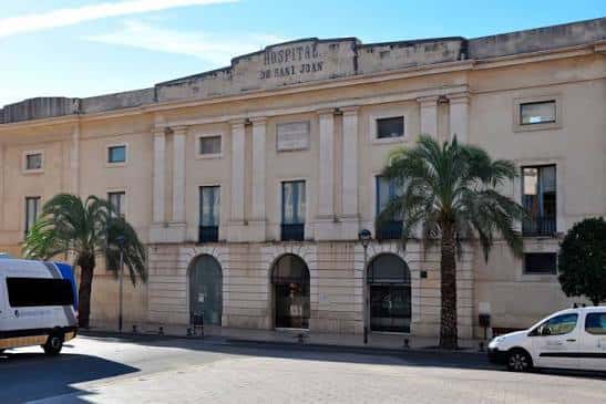Fachada principal del edificio histórico durante el día con vehículos en primer plano