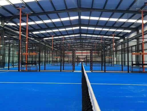 Vista interior de las pistas de pádel con suelo azul y estructura metálica