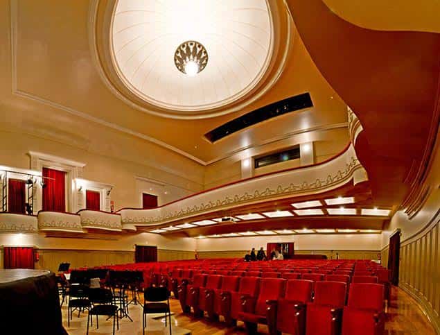 Interior del auditorio con butacas rojas, balcones ornamentados y gran cúpula central