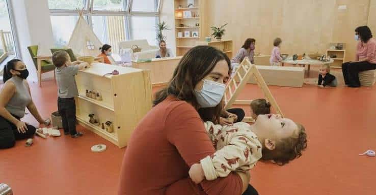 Madre sosteniendo a un bebé en una sala de actividades familiares