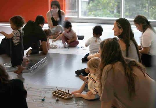 Taller de juego libre con niños y adultos sentados en círculo
