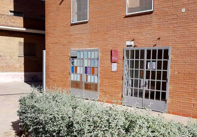 Entrada principal del edificio con puertas metálicas y cartel identificativo