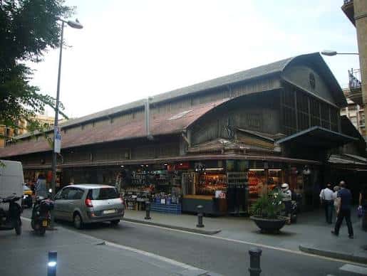 Fachada tradicional del mercado con estructura metálica y puestos visibles en la calle