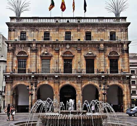 Fachada principal del Ayuntamiento con fuente al frente y banderas ondeando