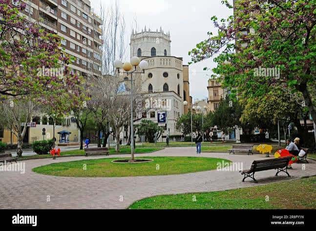 Vista panorámica de la Plaza Cardona Vives con el campanario de la iglesia al fondo y árboles en flor