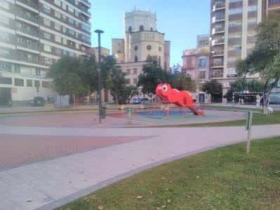 Plaza Cardona Vives con escultura roja de un animal y la torre de la iglesia en el fondo
