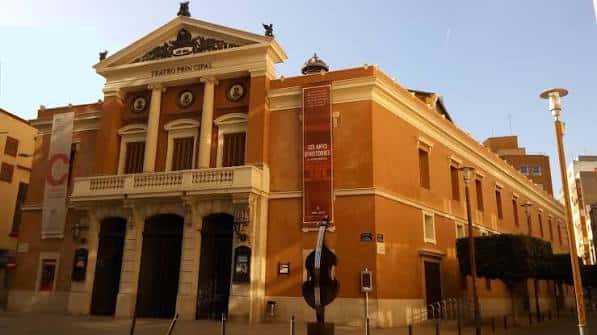 Exterior del Teatro Principal al atardecer con iluminación cálida y banderines decorativos