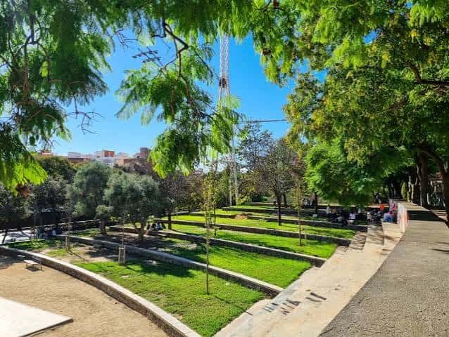 Vista panorámica del parque con zonas ajardinadas y personas disfrutando del espacio