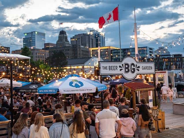Vista general del Beer Garden de Halifax al atardecer con banderas canadienses y luces decorativas